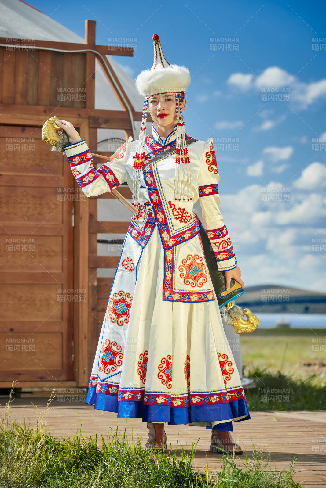 草原湖畔身穿蒙古族饰手持弓箭的蒙族少女图片