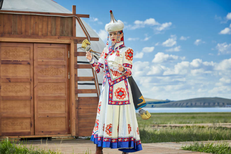 草原湖畔身穿蒙古族饰手持弓箭的蒙族少女图片