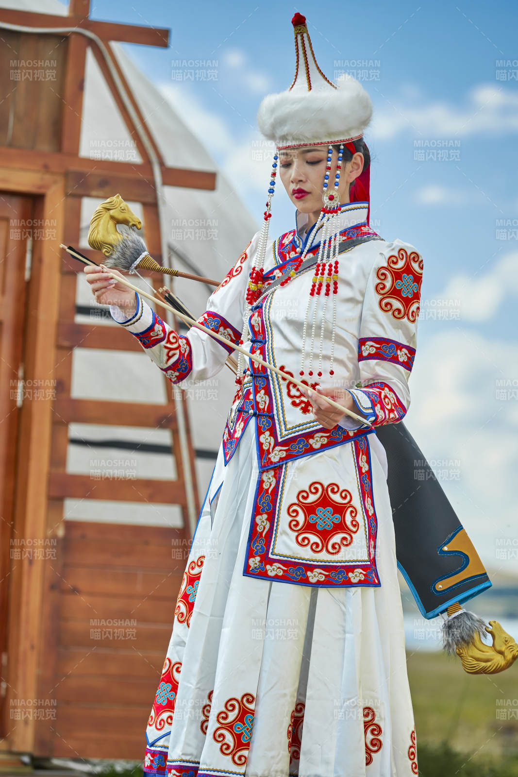 草原湖畔身穿蒙古族饰手持弓箭的蒙族少女图片