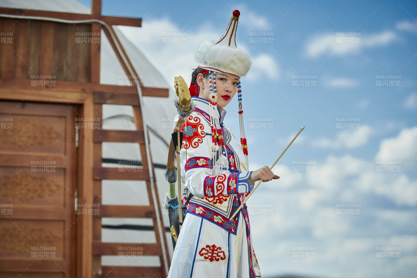 草原湖畔身穿蒙古族饰手持弓箭的蒙族少女图片