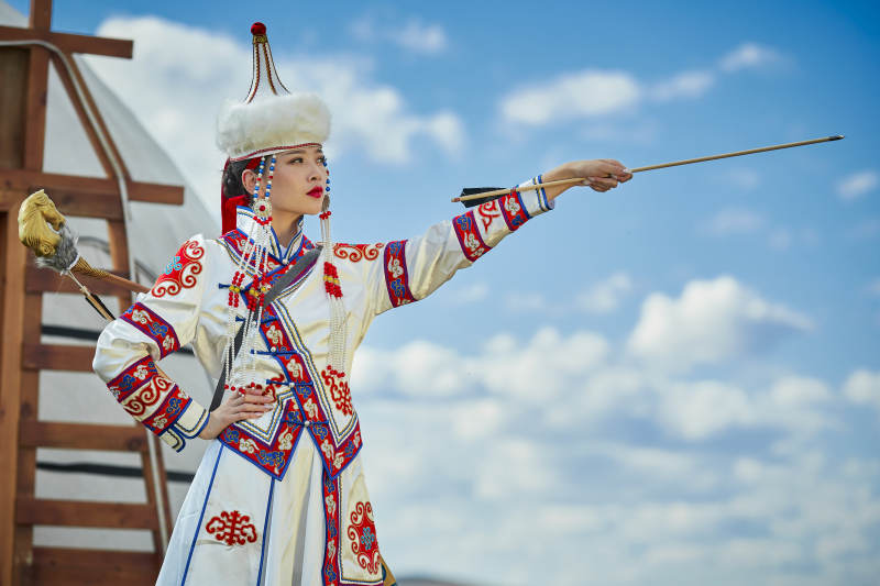 草原湖畔身穿蒙古族饰手持弓箭的蒙族少女图片
