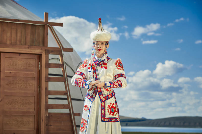 草原湖畔身穿蒙古族饰手持弓箭的蒙族少女图片