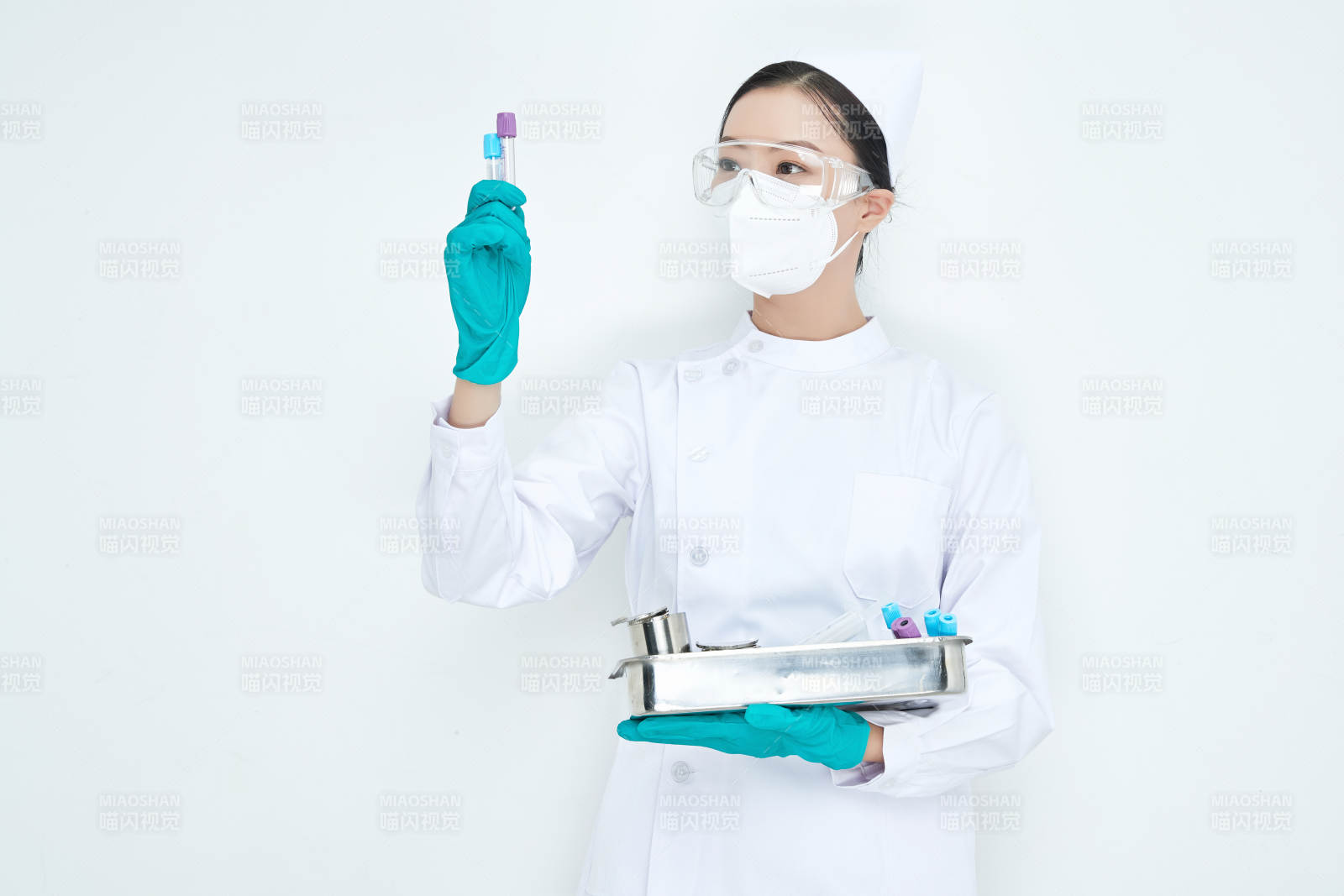 身穿护士服手抱化验托盘的年轻女护士图片
