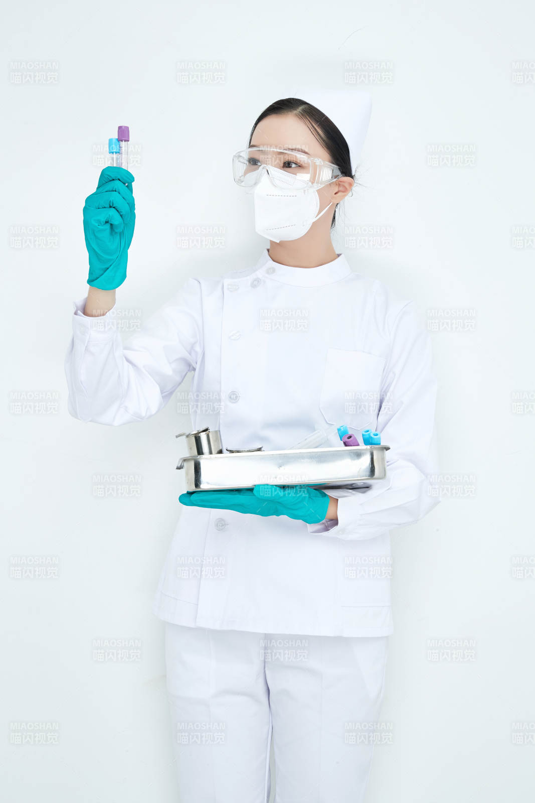 身穿护士服手抱化验托盘的年轻女护士图片