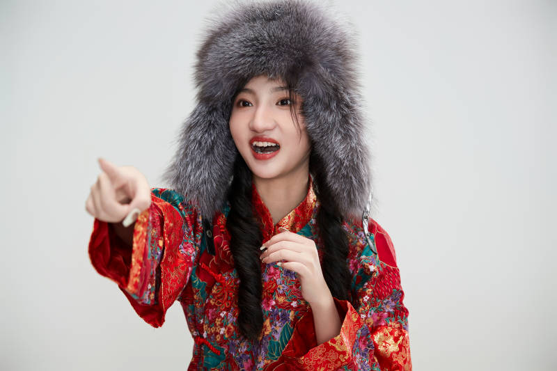 白色背景下穿中国传统服饰头戴绒帽的少女图片