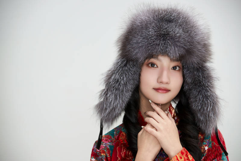 白色背景下穿中国传统服饰头戴绒帽的少女图片