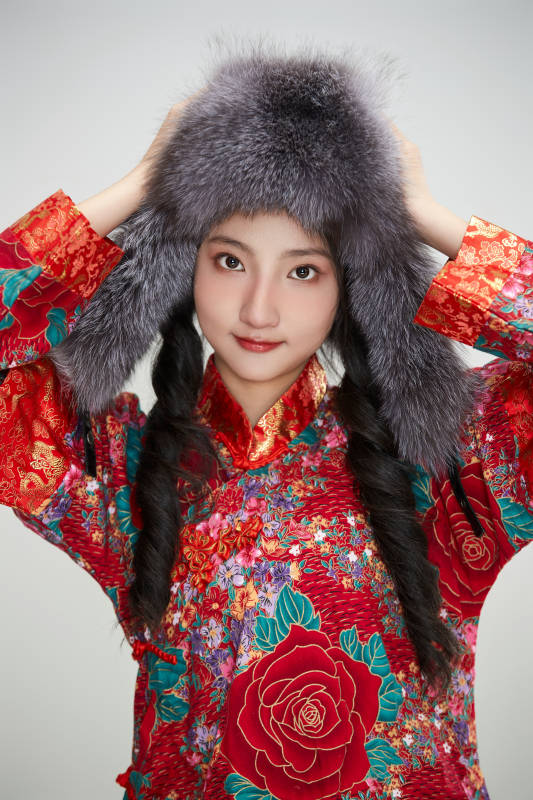 白色背景下穿中国传统服饰头戴绒帽的少女图片