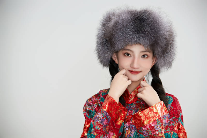 白色背景下穿中国传统服饰头戴绒帽的少女图片