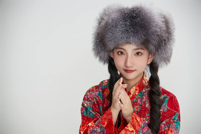 白色背景下穿中国传统服饰头戴绒帽的少女图片