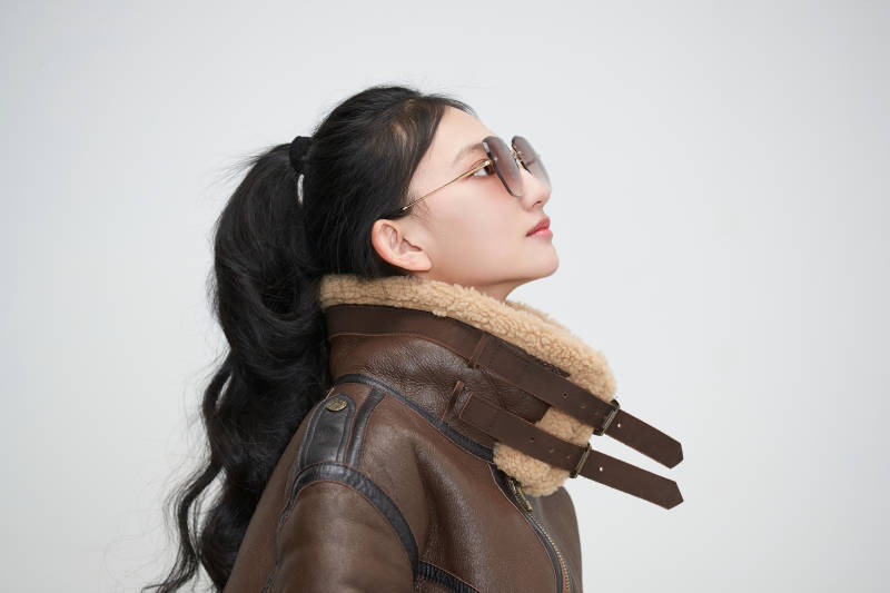 爱色背景下身穿飞行员皮夹克戴墨镜的可爱少女图片