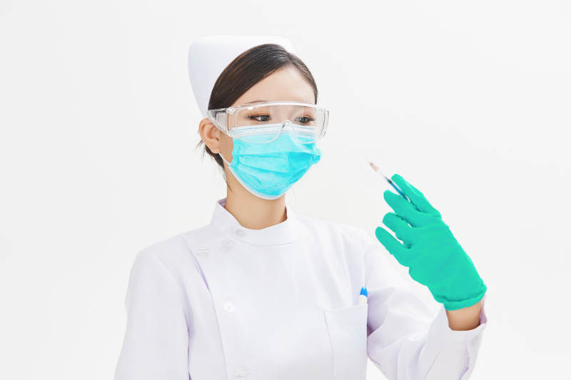 穿护士服戴口罩手执针筒的年轻女护士图片