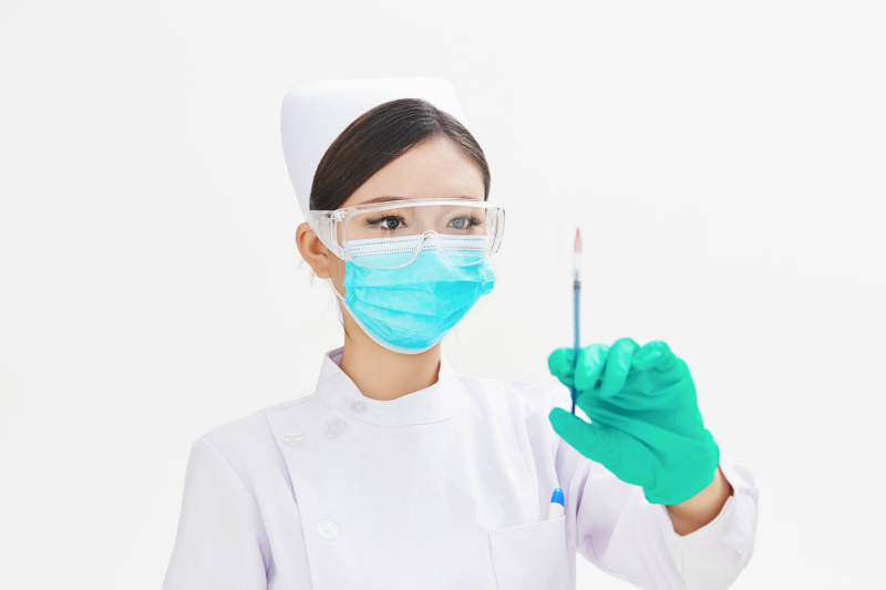 穿护士服戴口罩手执针筒的年轻女护士图片