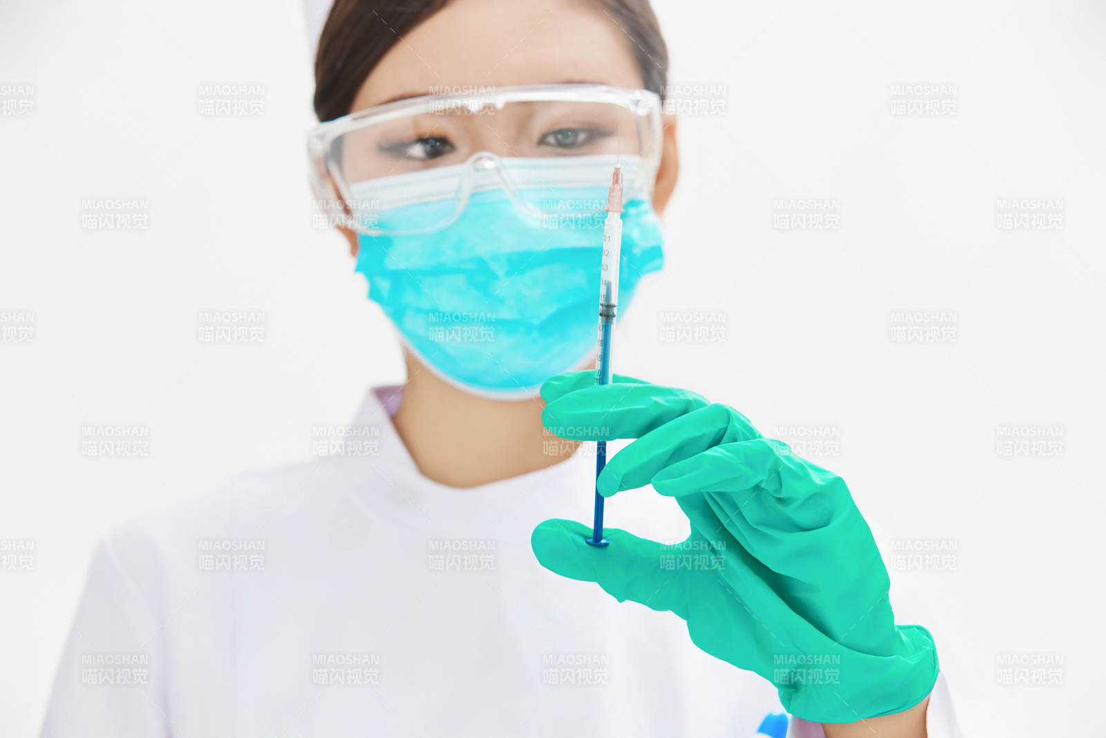 穿护士服戴口罩手执针筒的年轻女护士图片