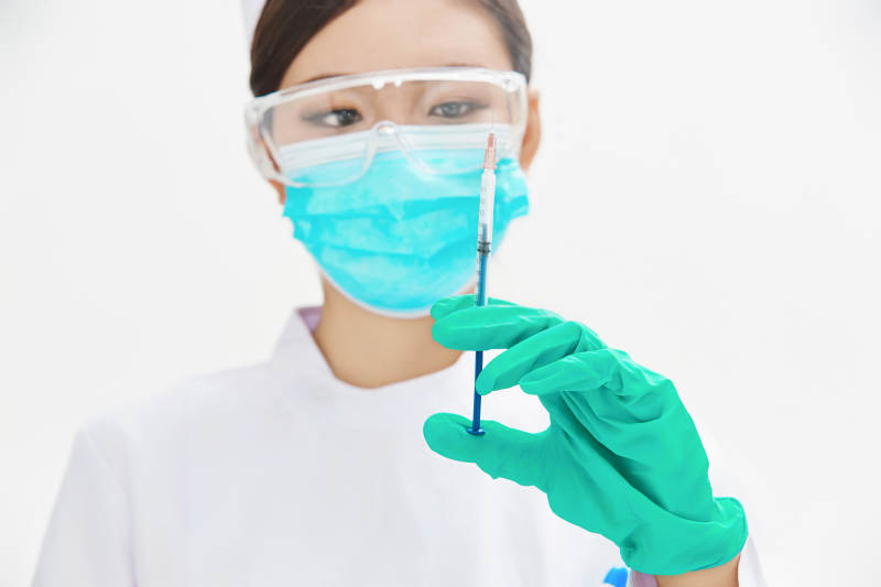 穿护士服戴口罩手执针筒的年轻女护士图片