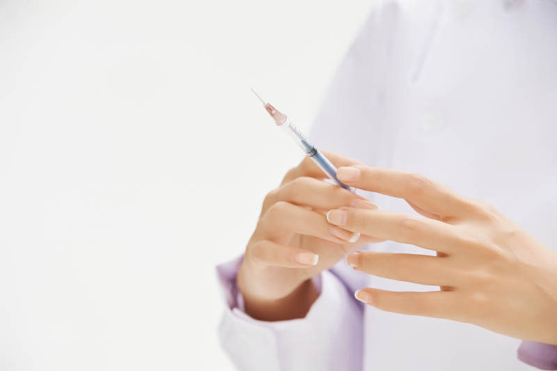 穿护士服戴口罩手执针筒的年轻女护士图片