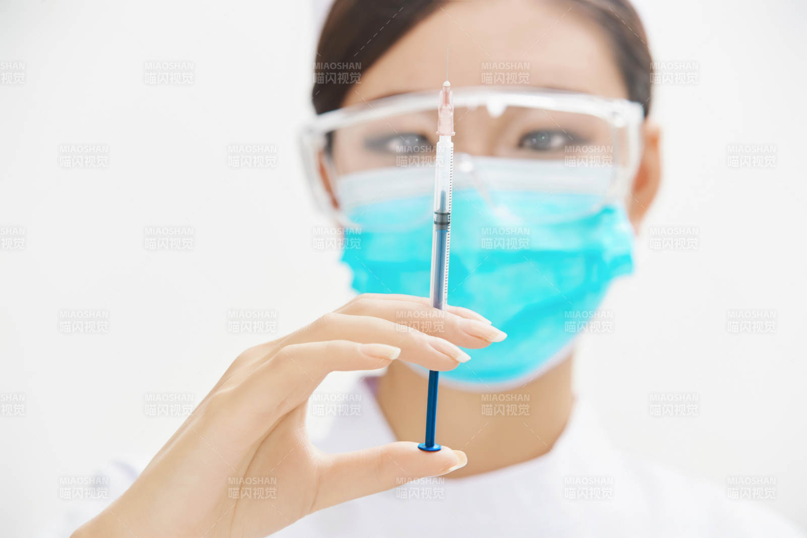 穿护士服戴口罩手执针筒的年轻女护士图片