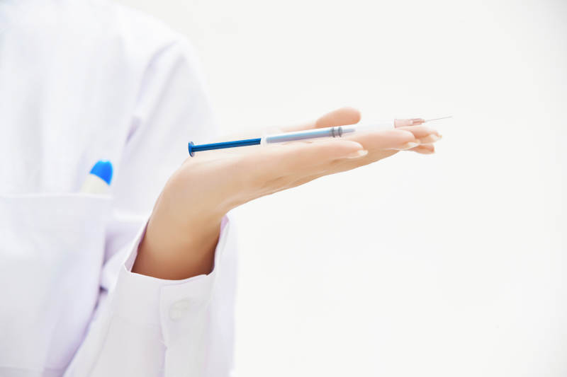 穿护士服戴口罩手执针筒的年轻女护士图片