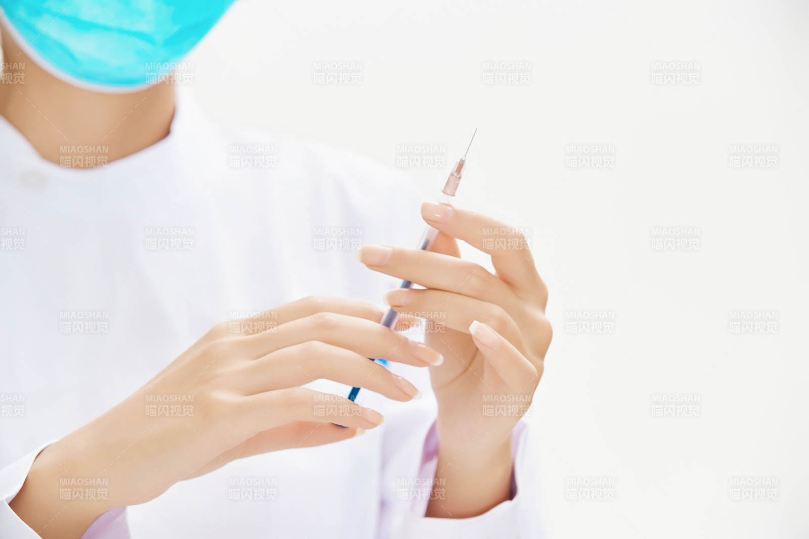 穿护士服戴口罩手执针筒的年轻女护士图片