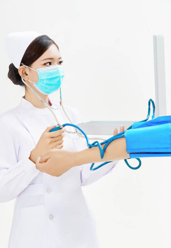 白色背景下手持血压计为患者测量血压的护士图片