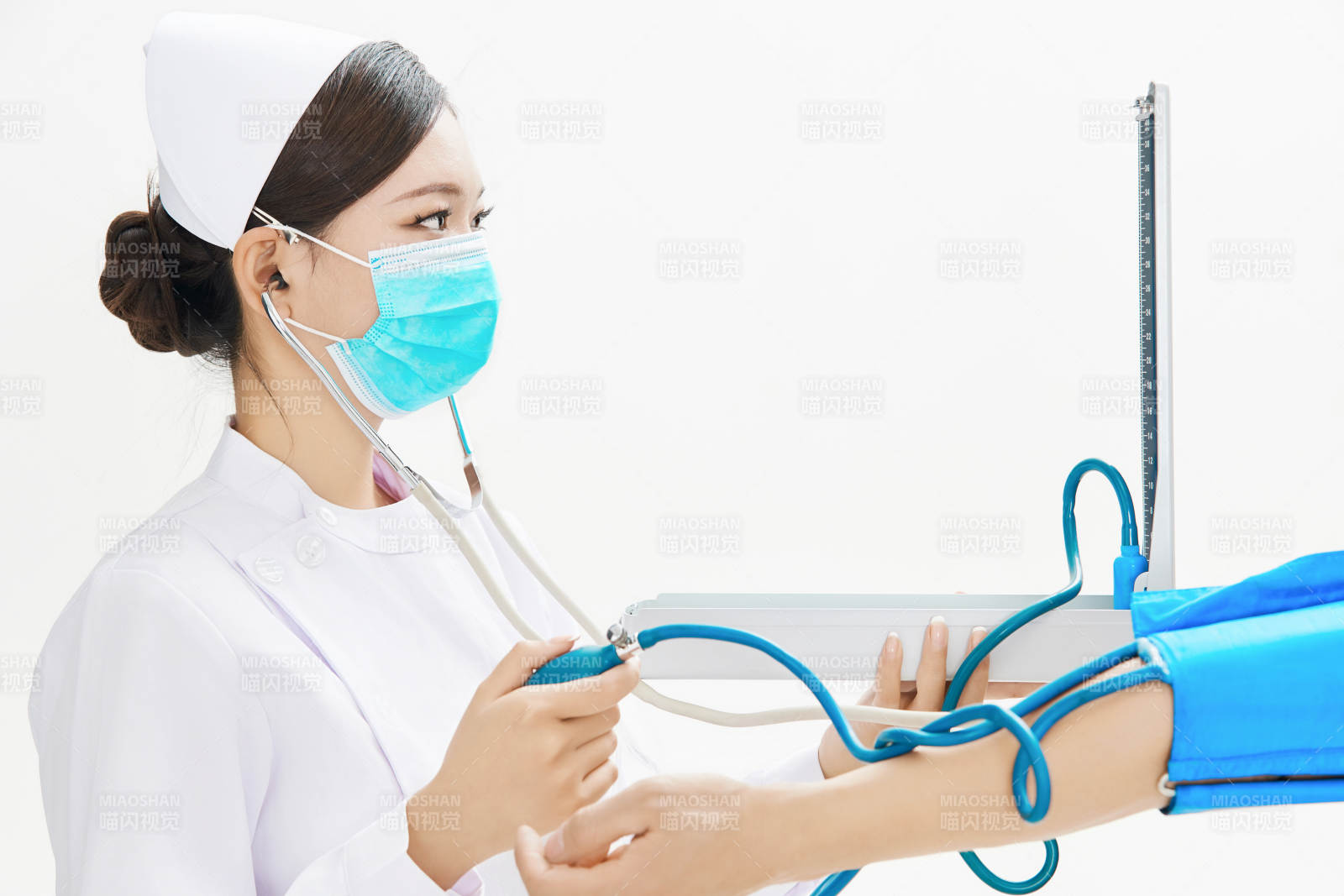 白色背景下手持血压计为患者测量血压的护士图片