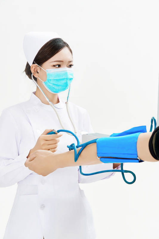 白色背景下手持血压计为患者测量血压的护士图片