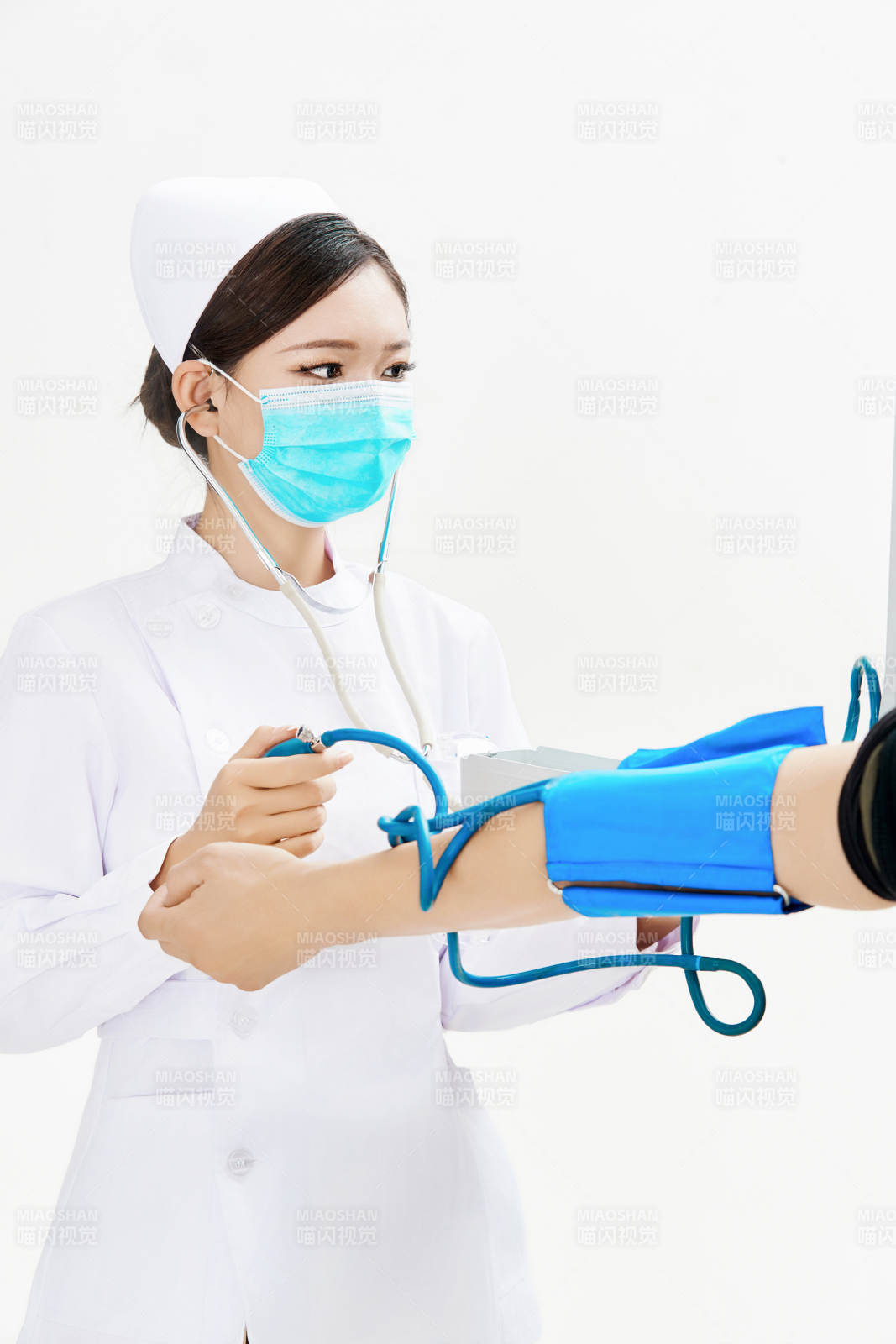 白色背景下手持血压计为患者测量血压的护士图片