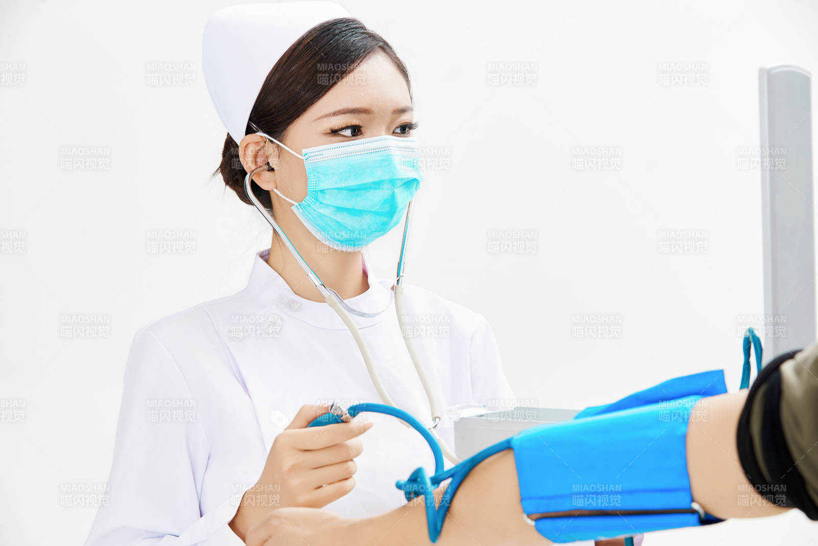 白色背景下手持血压计为患者测量血压的护士图片