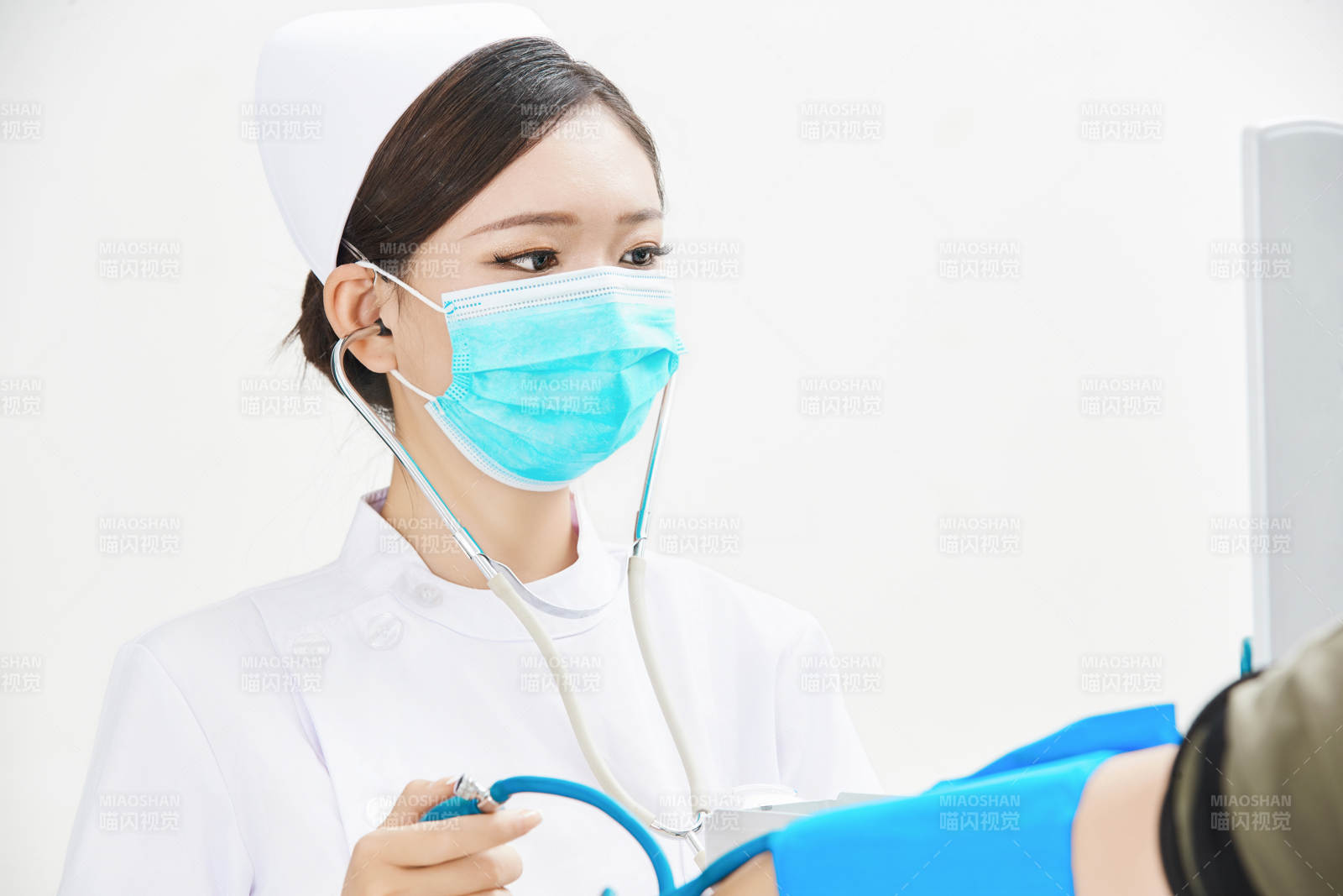 白色背景下手持血压计为患者测量血压的护士图片