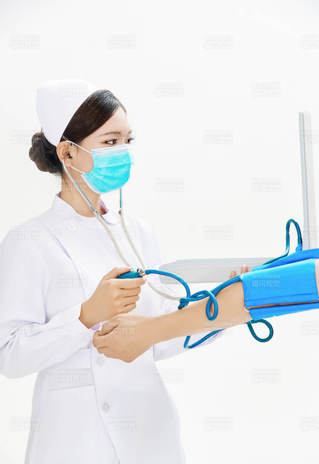 白色背景下手持血压计为患者测量血压的护士图片