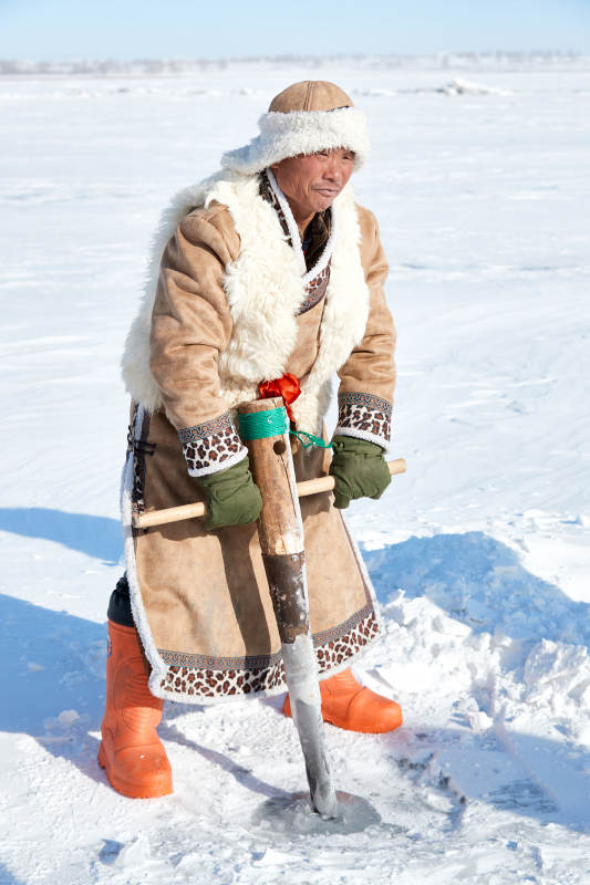寒冷的冬季在冰冻的湖面上凿冰捕鱼的人们图片