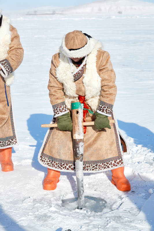 寒冷的冬季在冰冻的湖面上凿冰捕鱼的人们图片