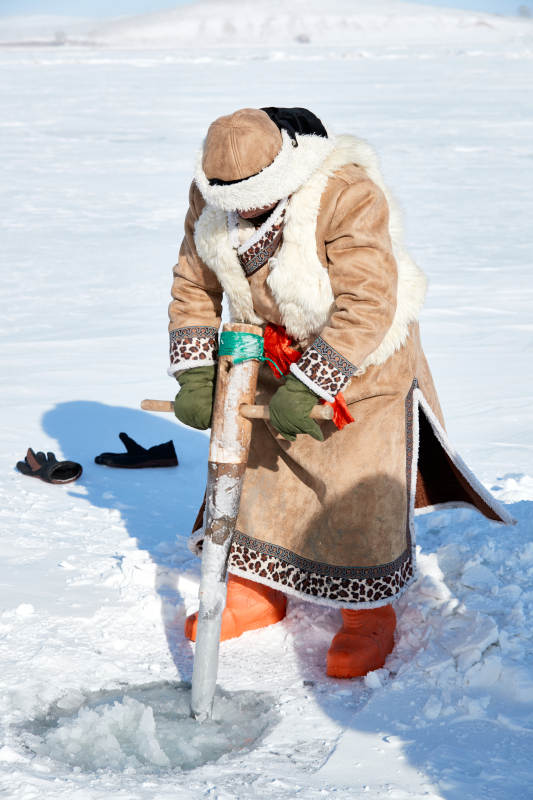 寒冷的冬季在冰冻的湖面上凿冰捕鱼的人们图片