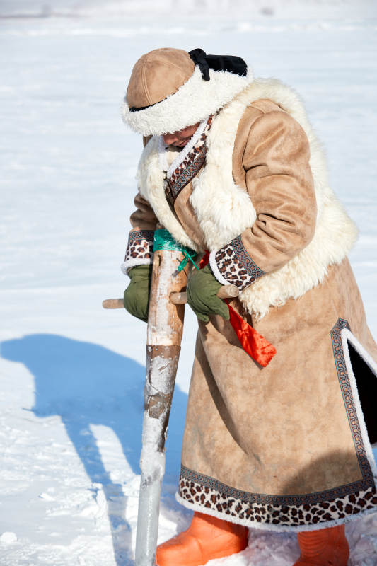 寒冷的冬季在冰冻的湖面上凿冰捕鱼的人们图片