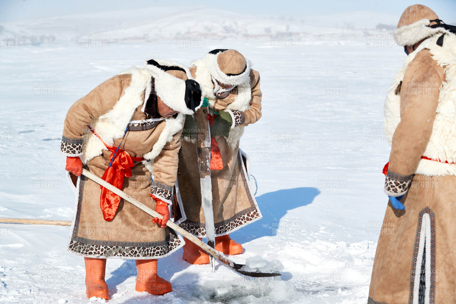 寒冷的冬季在冰冻的湖面上凿冰捕鱼的人们图片