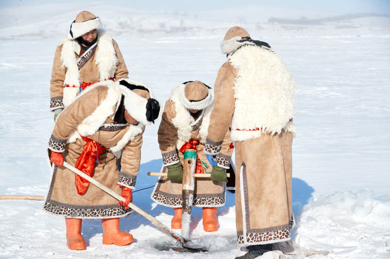 寒冷的冬季在冰冻的湖面上凿冰捕鱼的人们图片