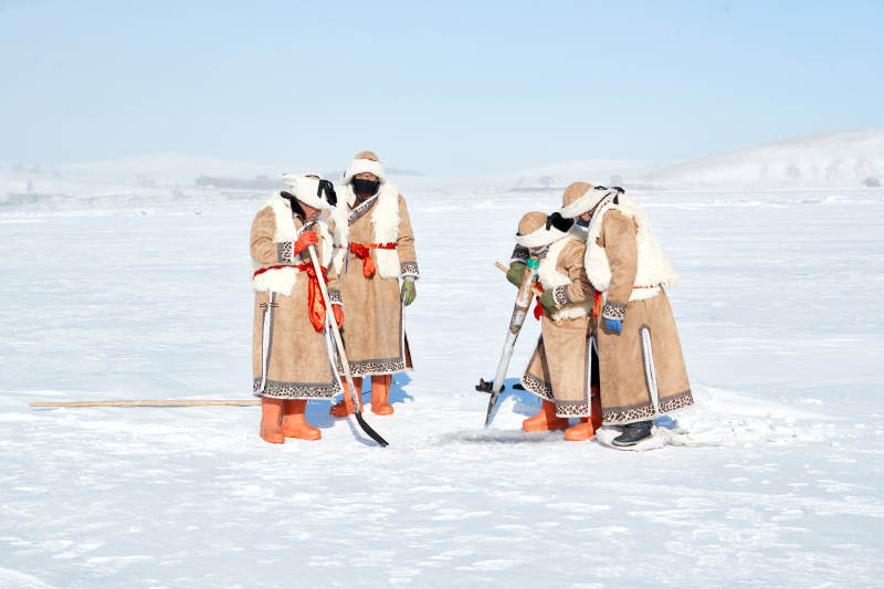 寒冷的冬季在冰冻的湖面上凿冰捕鱼的人们图片