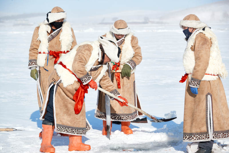 寒冷的冬季在冰冻的湖面上凿冰捕鱼的人们图片