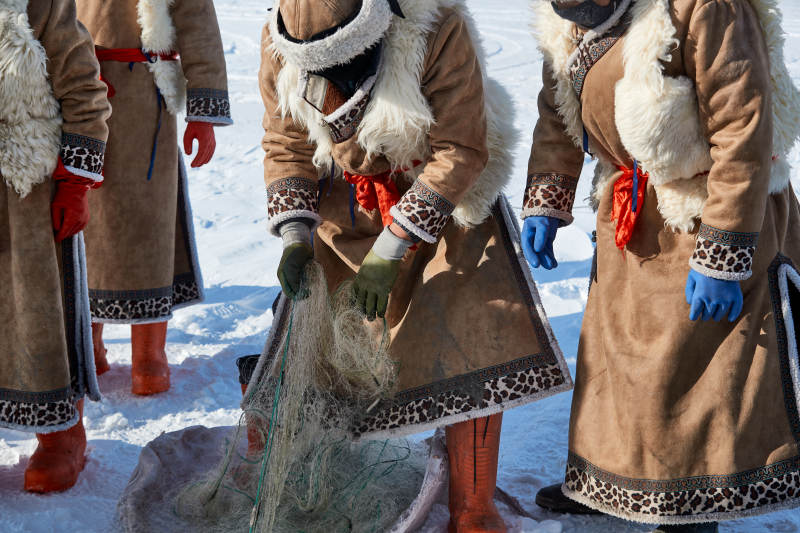 寒冷的冬季在冰冻的湖面上凿冰捕鱼的人们图片