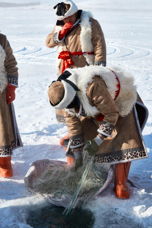 寒冷的冬季在冰冻的湖面上凿冰捕鱼的人们图片