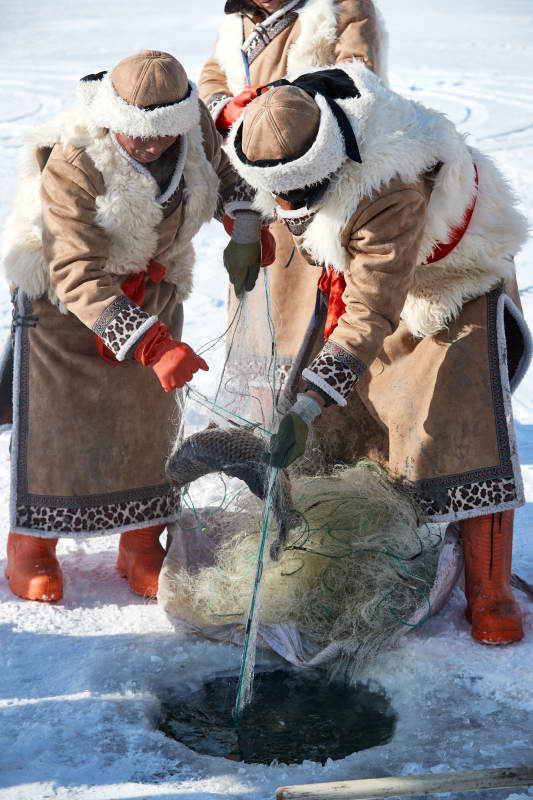 寒冷的冬季在冰冻的湖面上凿冰捕鱼的人们图片