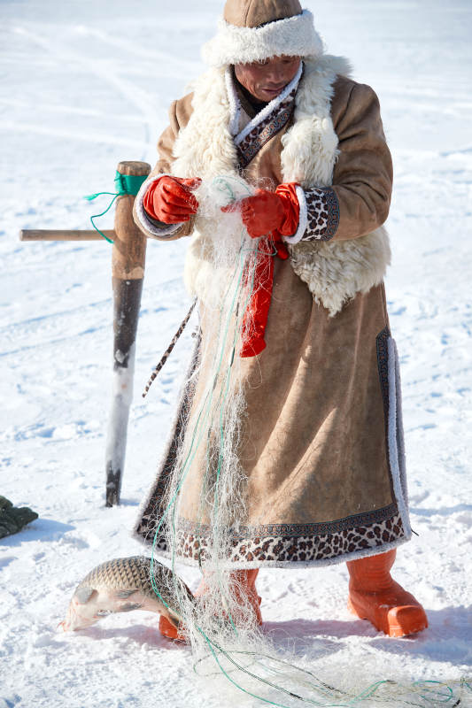 寒冷的冬季在冰冻的湖面上凿冰捕鱼的人们图片