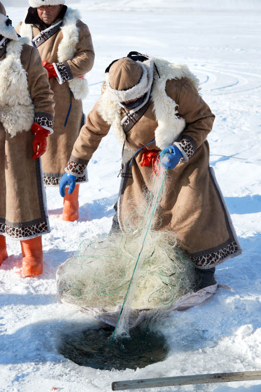 寒冷的冬季在冰冻的湖面上凿冰捕鱼的人们图片