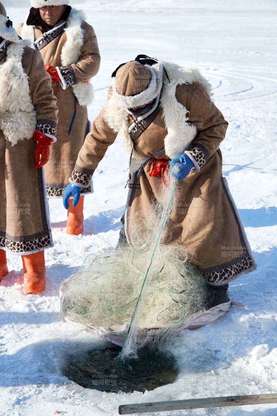 寒冷的冬季在冰冻的湖面上凿冰捕鱼的人们图片