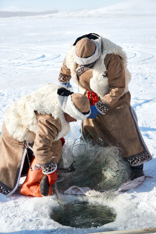 寒冷的冬季在冰冻的湖面上凿冰捕鱼的人们图片