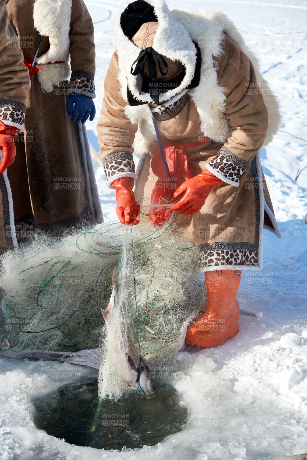 寒冷的冬季在冰冻的湖面上凿冰捕鱼的人们图片