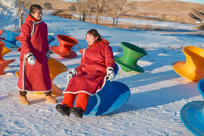 在冰天雪地玩耍雪上娱乐载具车辆的闺蜜少女图片