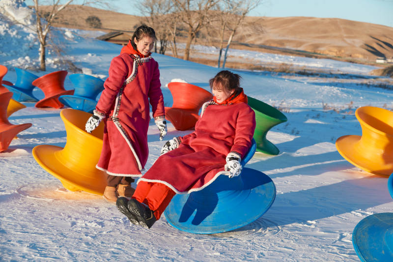 在冰天雪地玩耍雪上娱乐载具车辆的闺蜜少女图片