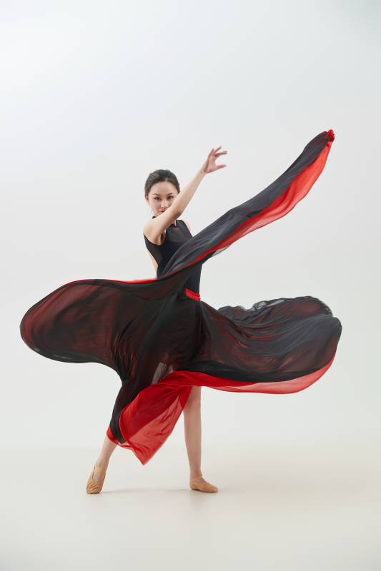 身穿红黑相间的舞蹈长裙翩翩起舞的少女图片