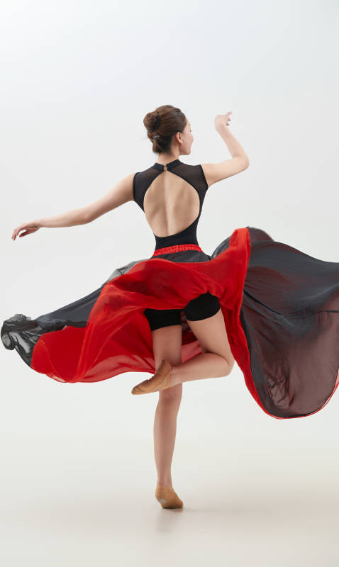 身穿红黑相间的舞蹈长裙翩翩起舞的少女图片