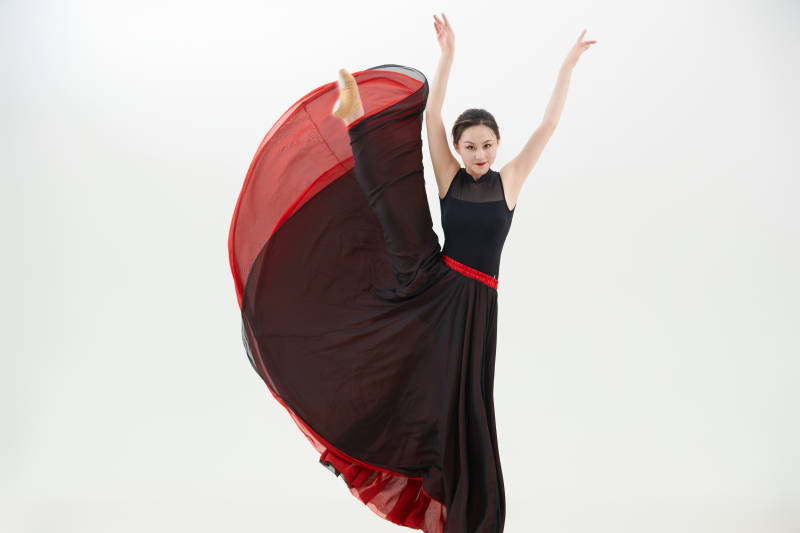 身穿红黑相间的舞蹈长裙翩翩起舞的少女图片